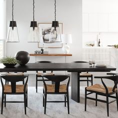 a dining room table and chairs in front of a window with an art work on the wall