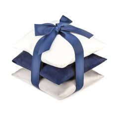 a stack of four pillows with blue ribbon on each one and white pillow cases stacked on top of each other