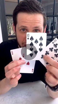 a man sitting at a table holding up playing cards