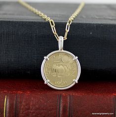 This 1970 India 20 Paise coin rests in a handcrafted setting made of recycled sterling silver wire.  I make each setting by hand separately from the coin.  The coin does not have a hole drilled in it or any metal soldered to its edge.   You may order the coin pendant with the gold-filled link chain featured in the photos. To order the pendant with the chain, choose Pendant with Chain under Select Option. To order the pendant without the chain, choose Pendant no Chain under Select Option. This coin was minted from 1968-1971 and demonetized in 2011.  The obverse of the coin features the Ashoka Lion Capital. The reverse features a lotus, the coin value, and the year. The metal content of the coin is nickel brass.  Approximate Size:  Necklace Length:  18 inches, Coin Setting Width: 1 inch, Coi Handmade Sterling Silver Coin Necklace, Sterling Silver Hallmarked Coin Necklace, Silver Coin Necklace For Anniversary, Anniversary Sterling Silver Coin Necklace, Sterling Silver Hallmarked Medallion Coin Necklace, Collectible Sterling Silver Coin Necklace With Round Pendant, Sterling Silver Coin Necklace With Round Pendant For Collectors, Sterling Silver Coin Necklace, Coin Frame