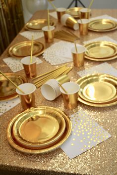 the table is set with gold and white plates, napkins, and paper straws