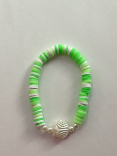 a green and white beaded bracelet with a shell charm on it's end