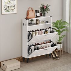 a white shoe rack filled with shoes next to a potted plant