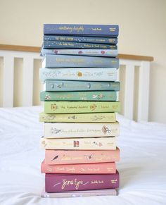 a stack of books sitting on top of a bed next to a white headboard