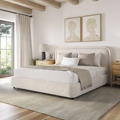 a large white bed sitting in a bedroom on top of a hard wood floor next to a window