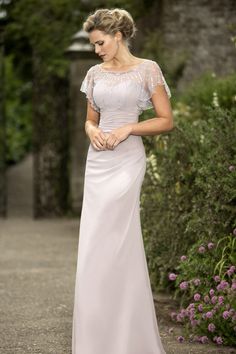 a woman in a white dress is standing outside