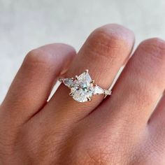 a woman's hand with a diamond ring on top of her finger and an engagement band