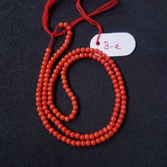 a red beaded necklace with a white tag on it