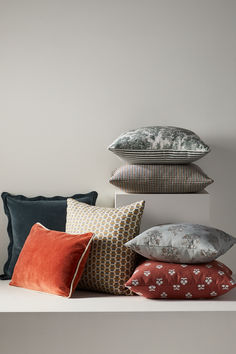 a pile of pillows sitting on top of a white shelf