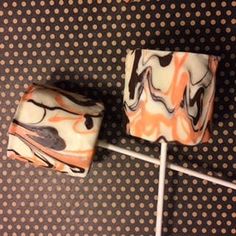 two lollipops sitting on top of a brown and white polka dot covered surface