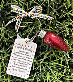 a christmas ornament with a message attached to it sitting in the grass next to a bottle of wine