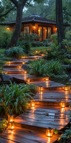 a wooden walkway with lit candles on it in the middle of some trees and plants