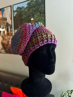 a knitted hat sitting on top of a mannequin's head in front of a painting