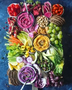 an array of vegetables and dips arranged in the shape of a letter