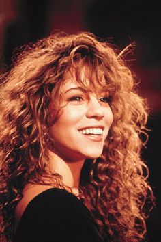 a woman with long curly hair smiling at the camera