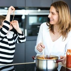 a mother and son are cooking in the kitchen together, one is holding a spoon