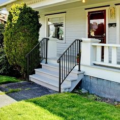 a small white house with stairs leading up to the front door