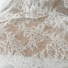 white lace with flowers on it is shown in close up view from the neck down