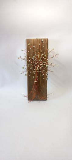 a vase with flowers in it sitting on a white surface next to a wooden wall