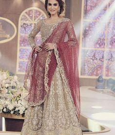 a woman in a red and white lehenga on the ramp at a fashion show