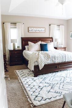 a bedroom with a bed, dressers and rug on the floor in front of it