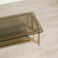 a glass coffee table with metal legs and a wooden frame on the bottom, sitting on a wood floor