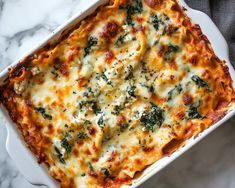 a casserole dish with cheese and spinach in it on a marble surface