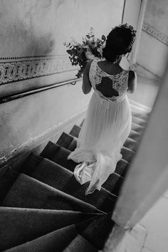 a woman in a white dress is walking down the stairs with flowers on her head