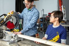 a man and boy are working on a table sawing project in a garage with tools