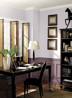 a home office with purple walls and wooden flooring, along with a bookcase full of books