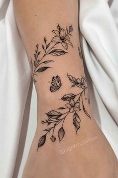 a woman's foot with flowers and leaves tattooed on the side of her leg