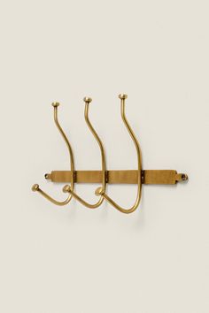 three brass hooks hang from the wall, with one hook on each side and two other hooks