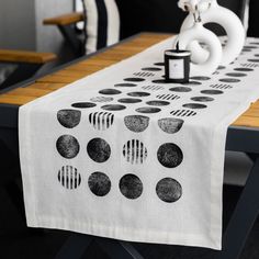 a white table with black polka dots on it and a candle in the middle next to it