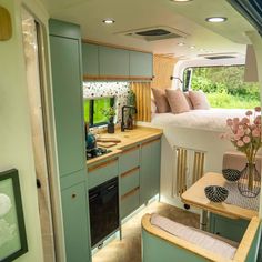 the interior of a camper with green cabinets and wood flooring