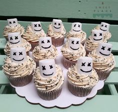 cupcakes with white frosting and black sprinkles are arranged on a plate