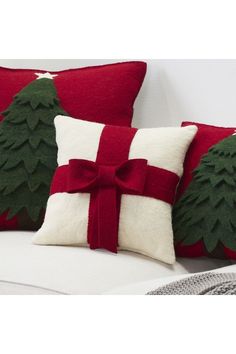 three pillows with christmas trees on them sitting on a couch next to a pillow case