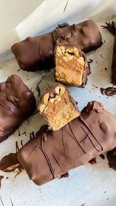 several pieces of chocolate covered dessert sitting on top of a white paper towel with some broken bars in the middle