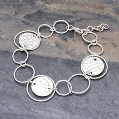 This stylish 950 silver link bracelet is presented by Pakaon Sojintarit who works with artisans of the Karen hill tribe in Thailand. Hammered discs join forces with polished round links in assorted sizes. The result is a fun contemporary accessory to wear anywhere. Modern Silver Round Disc Jewelry, Modern Sterling Silver Round Chain Bracelet, Modern Hammered Round Bracelets, Modern Silver Round Chain Bracelet, Modern Sterling Silver Bracelets For Jewelry Making, Adjustable Round Chain Bracelet With Polished Finish, Modern Round Sterling Silver Bracelets, Sterling Silver Hammered Bracelets, Hammered Sterling Silver Round Bracelets