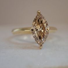 a fancy yellow diamond ring sitting on top of a white countertop next to a wall