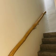 a wooden hand rail on the side of a stair case next to a wall and carpeted floor