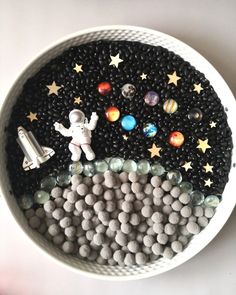 a bowl filled with black and white candies next to an astronaut's space shuttle