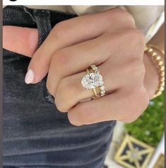 a woman's hand wearing a gold ring with an oval shaped diamond on it