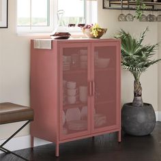 a pink cabinet sitting next to a potted plant