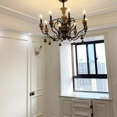 a chandelier hanging from the ceiling in a room with white walls and windows