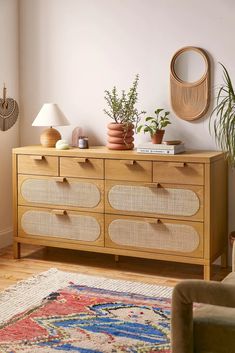 a wooden dresser with baskets on top and plants in the bottom drawer next to it