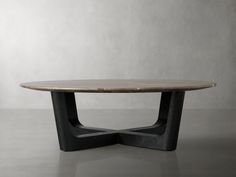 an oval table with black legs and a wooden top on a gray floor in front of a white wall