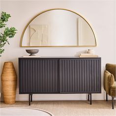 a black and gold sideboard in a living room with a round mirror above it