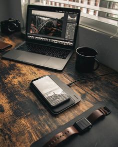 an open laptop computer sitting on top of a wooden desk next to a cup of coffee