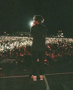 a man standing on top of a stage in front of an audience at a concert