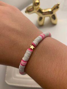 a person's arm with a bracelet on it and a gold toy in the background